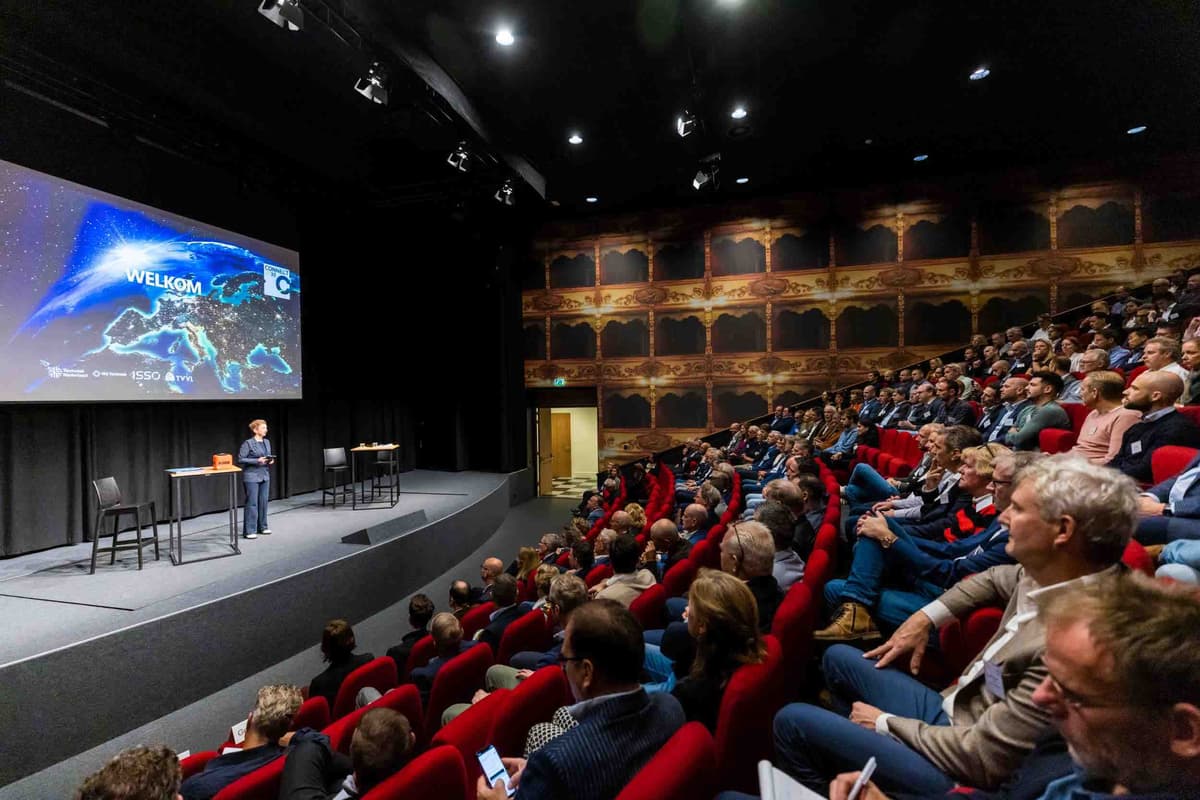 Marijke Roskam aan het spreken op een podium voor publiek in een zaal