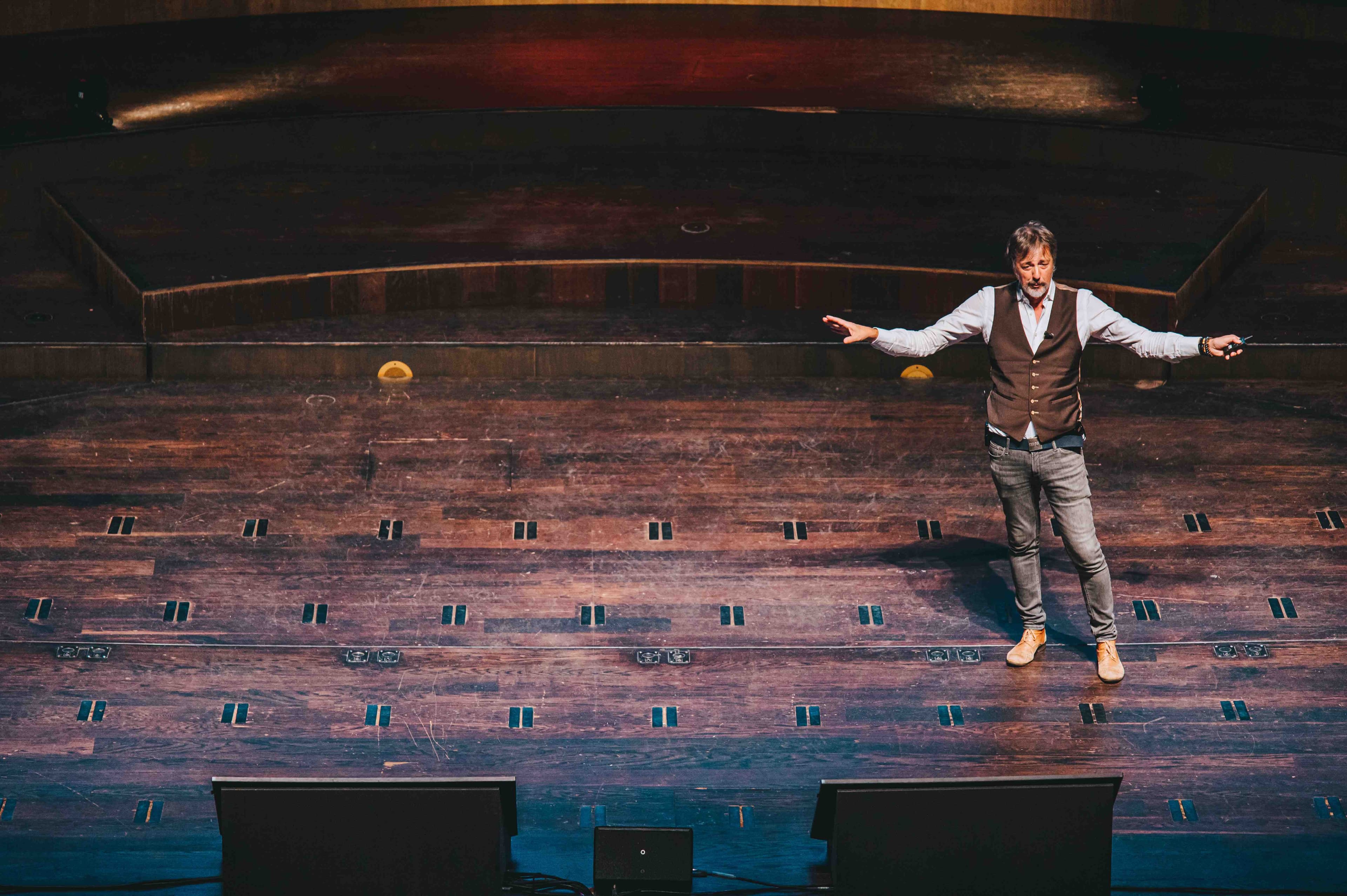 Rik Vera op een podium met een uitleggende open houding