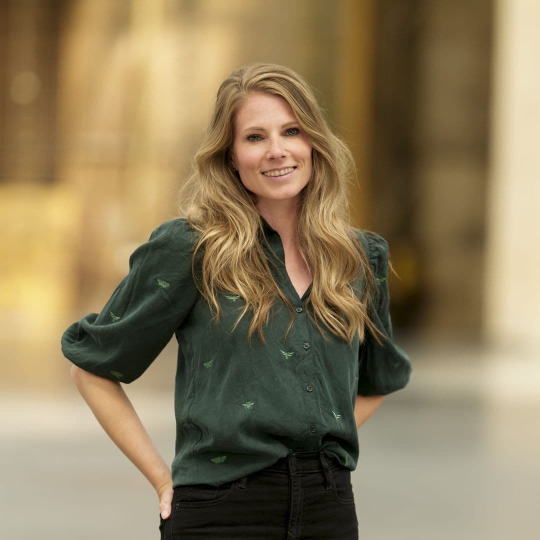 Anouk Bienefelt glimlachend in groene blouse met handen in achterzakken