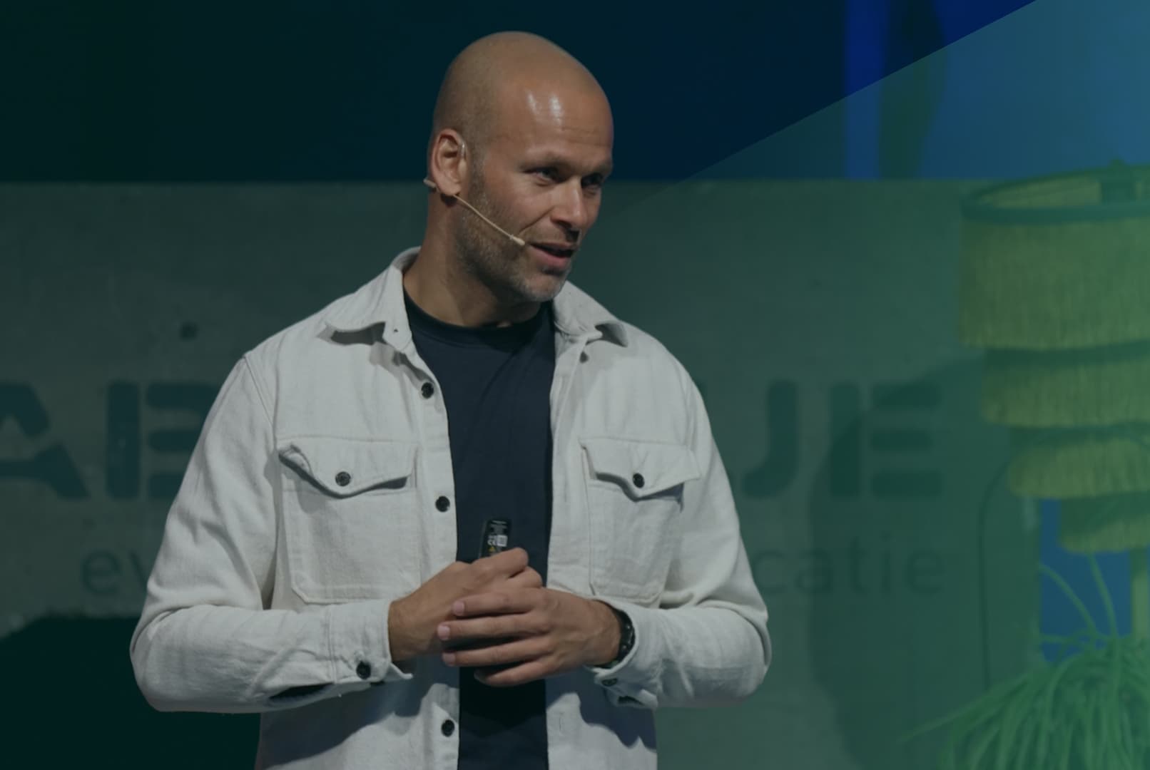 Renaldo Ishaak in witte spijkerjas aan het spreken met groene gloed over zich