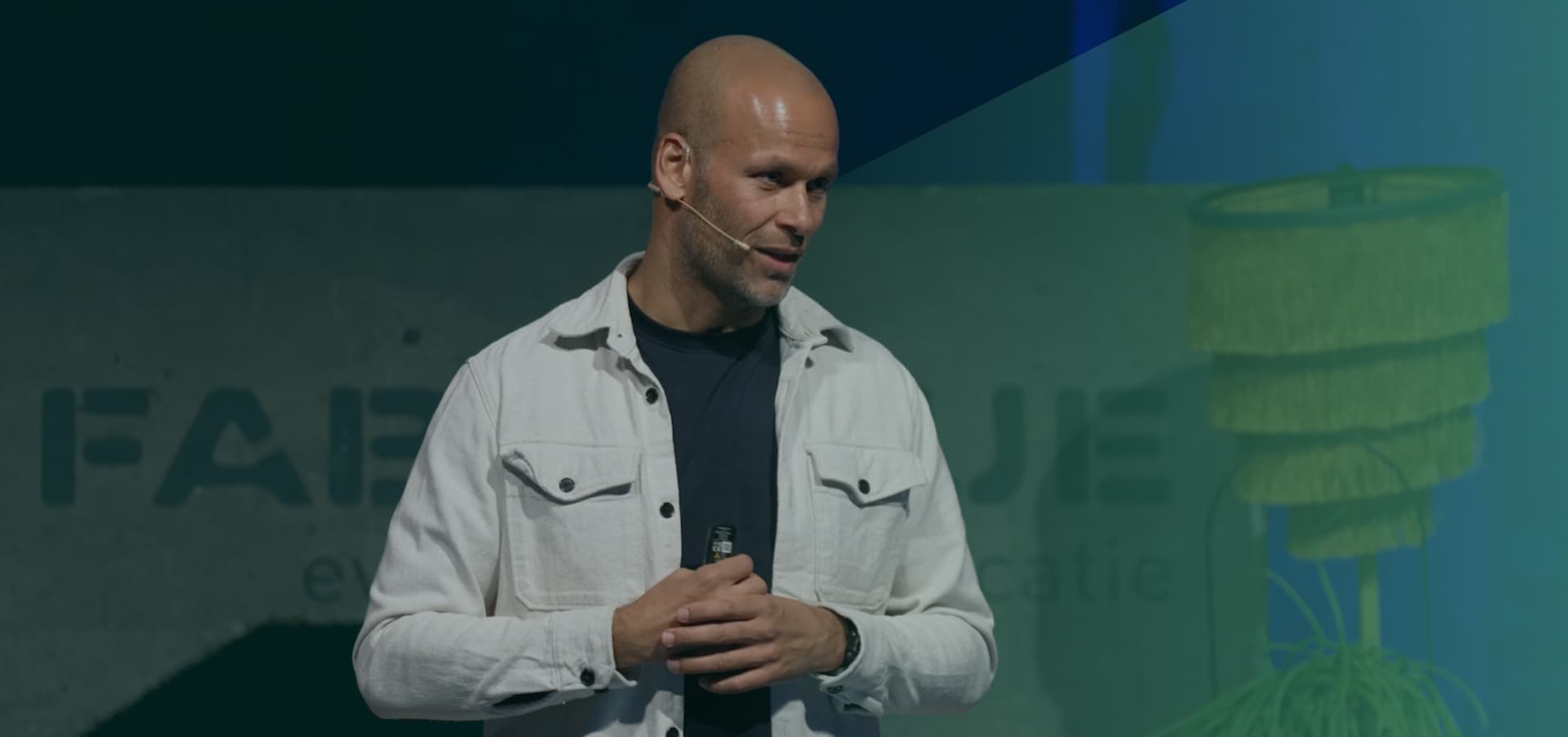 Renaldo Ishaak in witte spijkerjas aan het spreken met groene gloed over zich