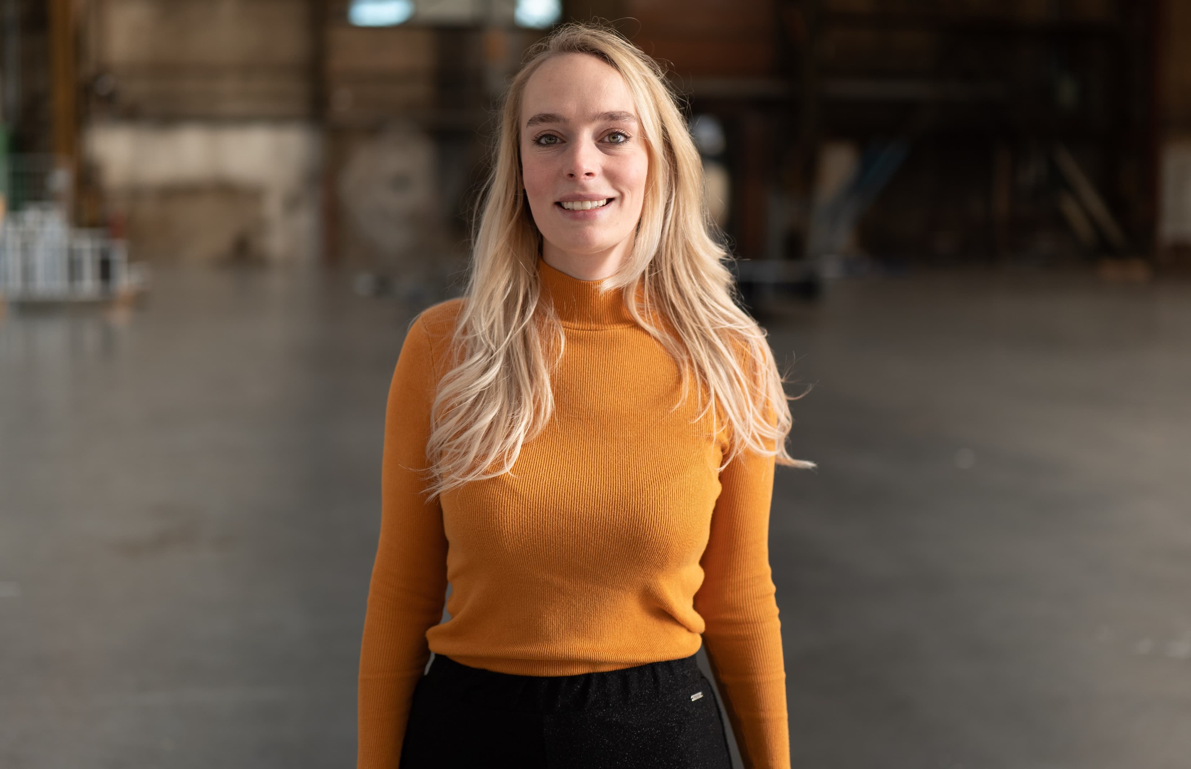 Adelitha van der Zee glimlachend poserend in oranje shirt en zwarte broek