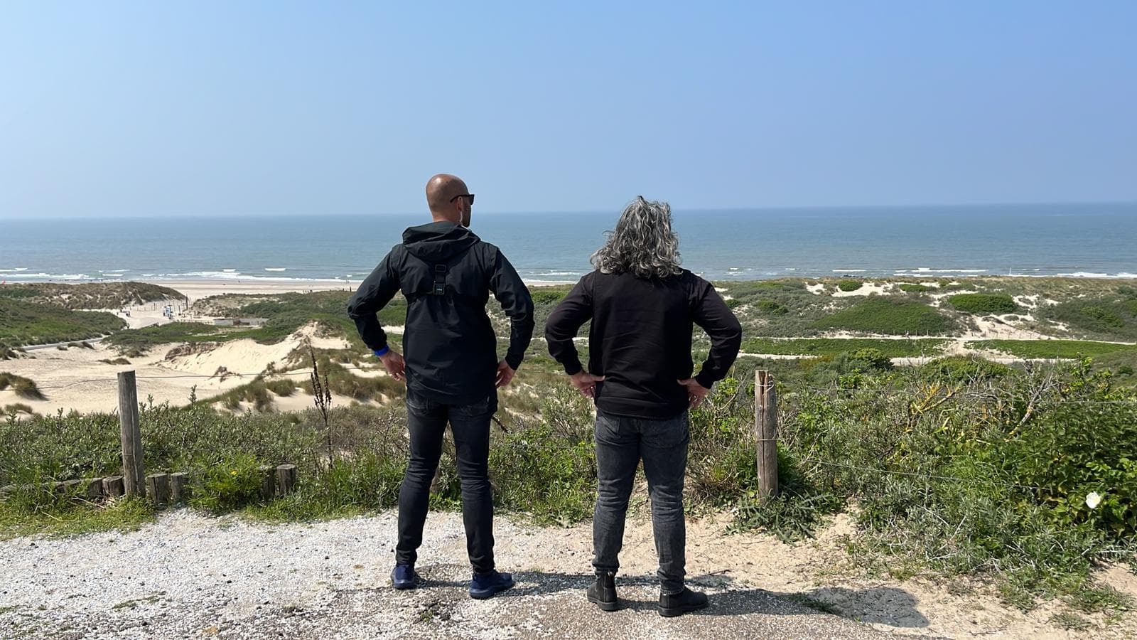 Renaldo Ishaak poserend met man kijkend naar duinen en zee