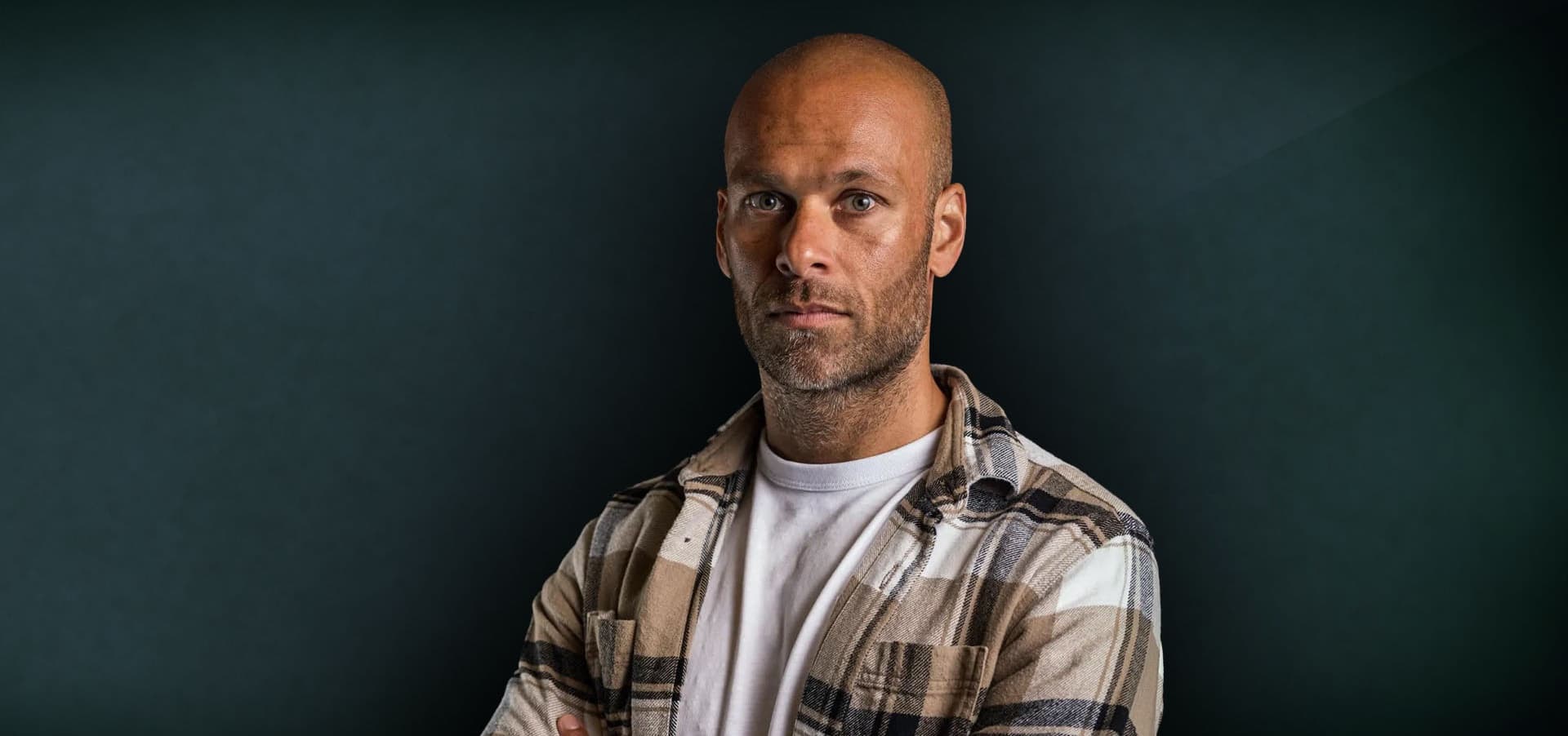 Renaldo Ishaak met armen over elkaar poserend bij groene achtergrond