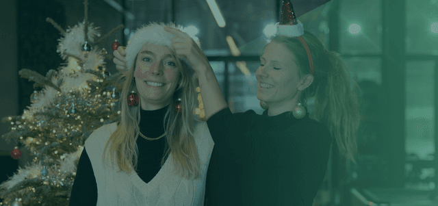 Verbinder Anouk die een kerstmuts op het hoofd van verbinder Adelitha zet