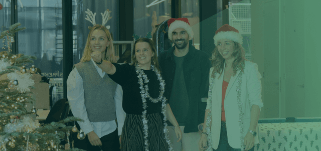 een man en drie vrouwen glimlachend in kerst accesoires met groene gloed over zich