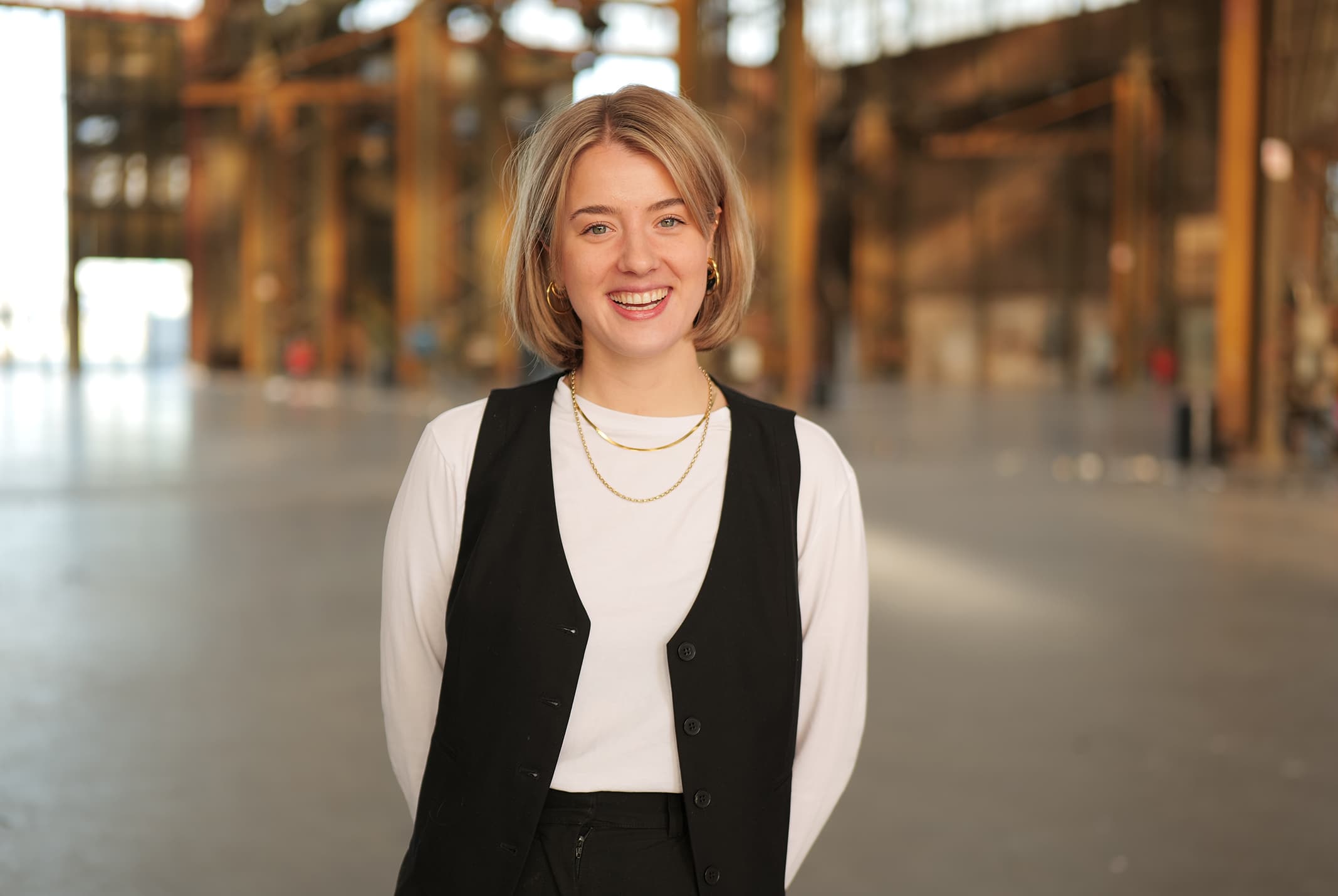 Maaike Somers lachend in witte shirt met handen achter rug