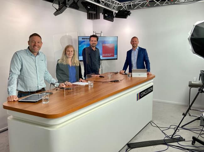 Robert Daverschot met twee mannen en een vrouw in studio achter een wit bureau