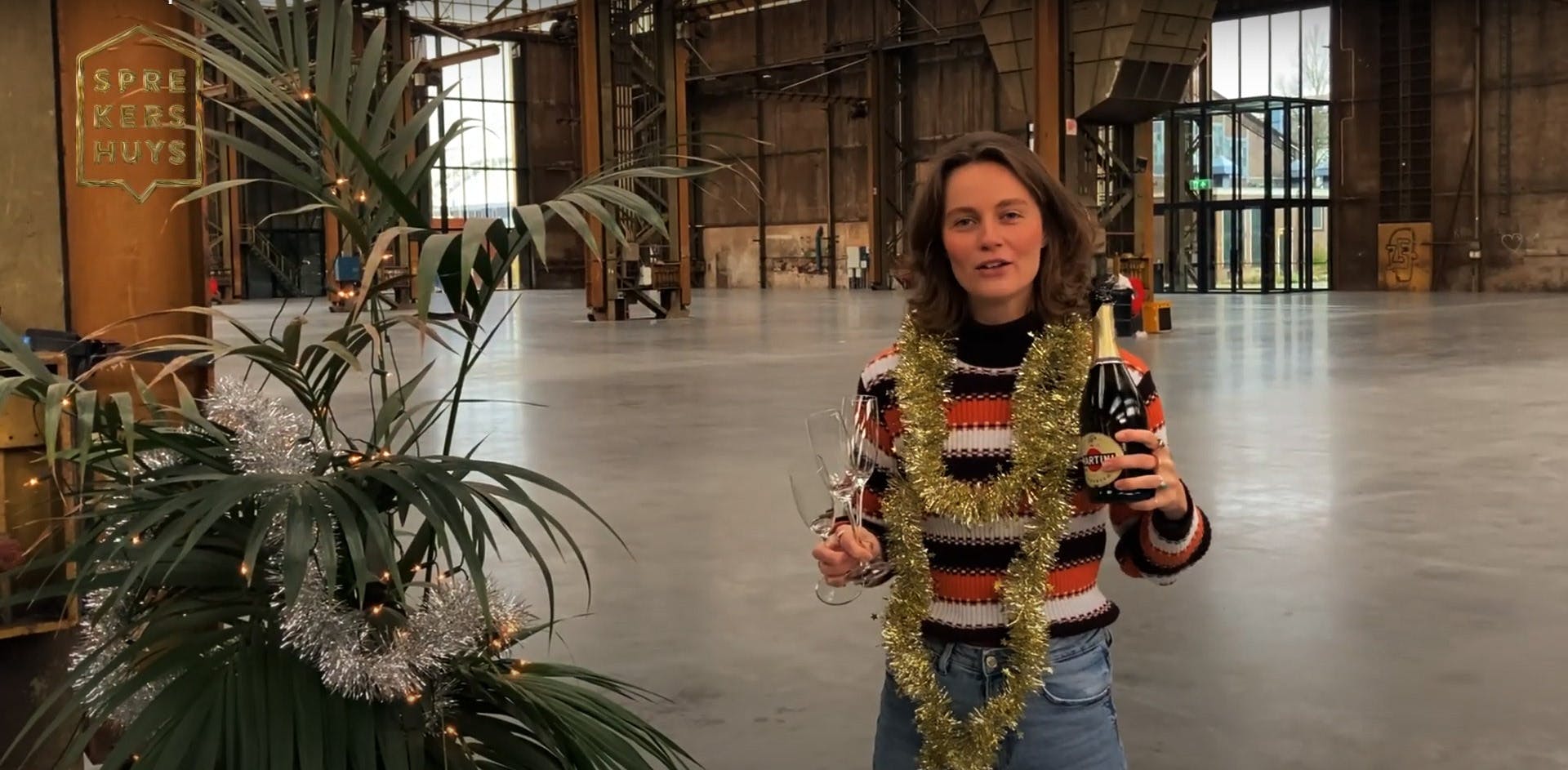 Vivian Goudkuil met kerstslingers om zich heen en champagne vast
