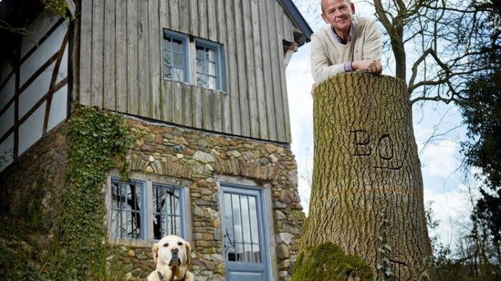 Bas Hoogland leunend tegen boomstronk met hond buiten