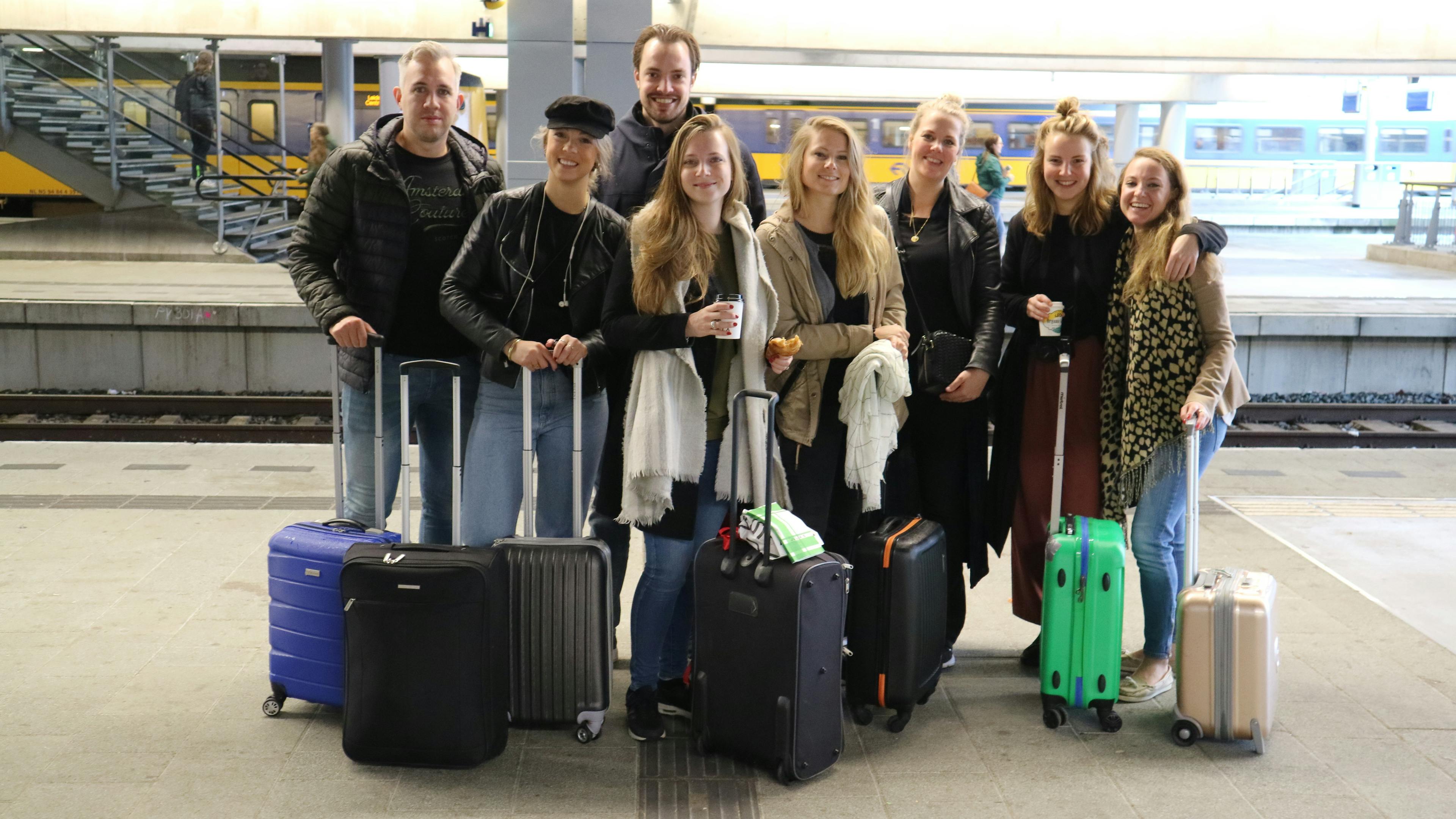 8 mensen van Sprekershuys op utrecht centraal met koffers glimlachend