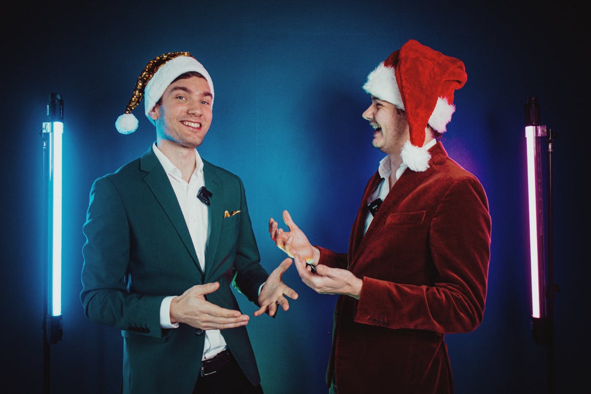 Remy Gieling in rood pak en Kees Dorrestijn in groen pak met kerstmutsen op glimlachend