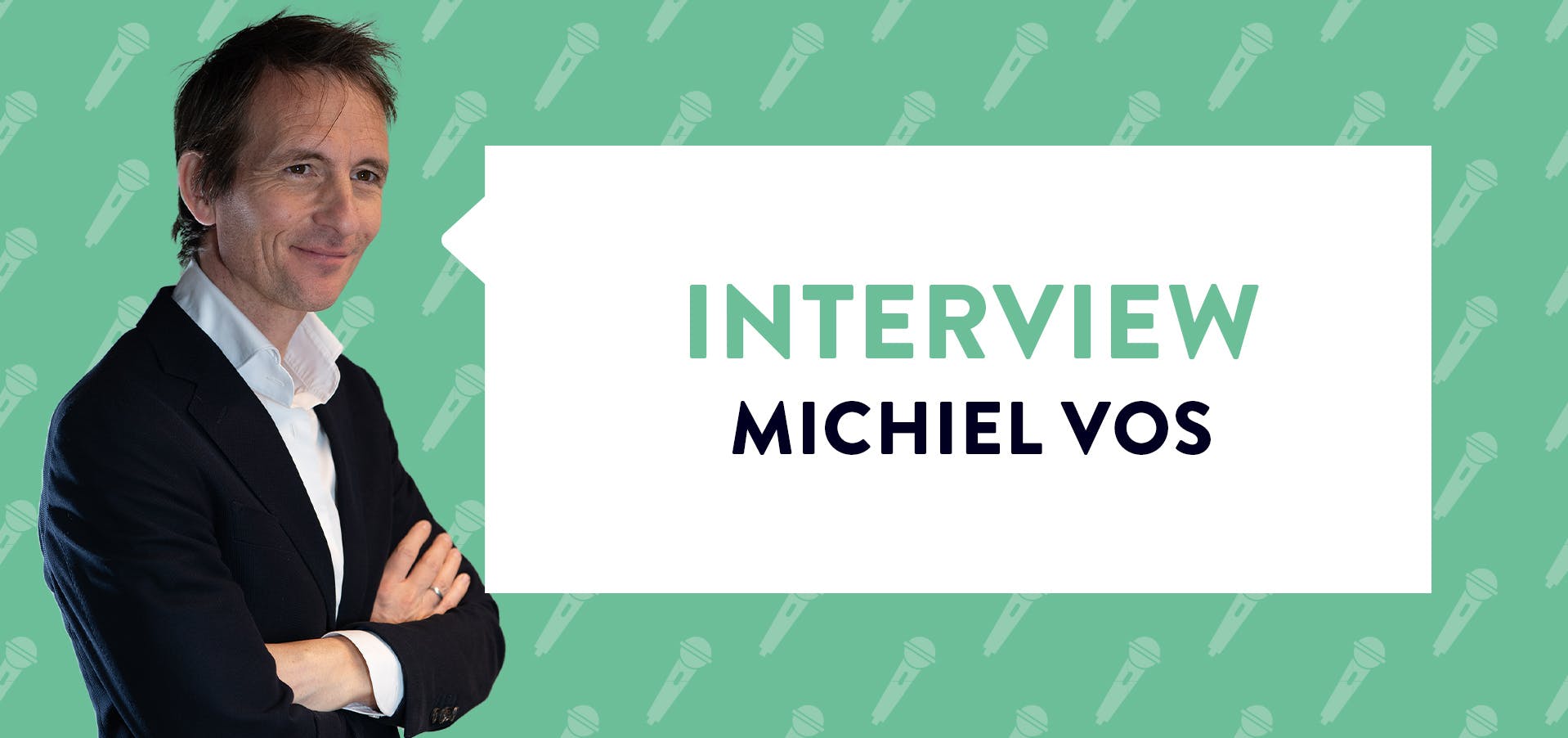 Michiel Vos met armen over elkaar glimlachend in zwart pak bij groene achtergrond met tekst 'interview michiel vos'