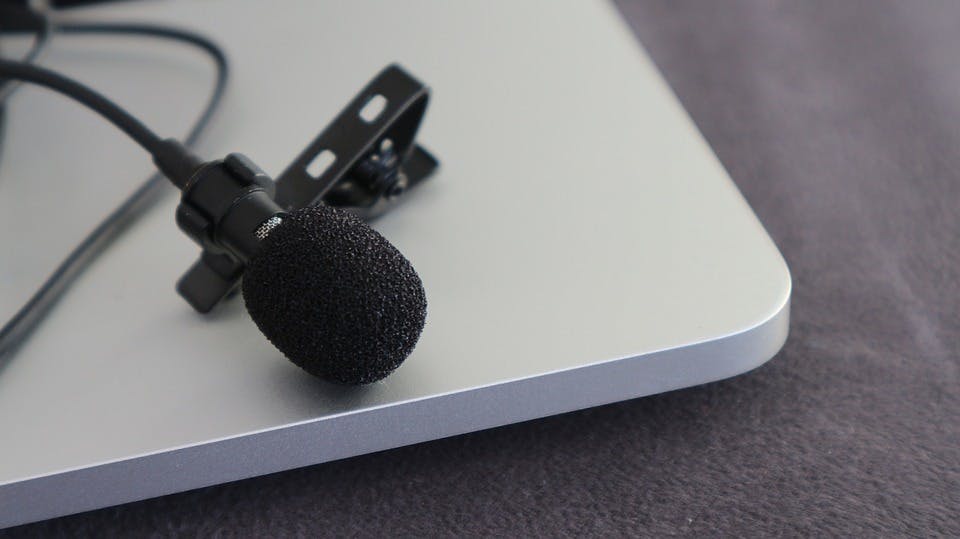 Microfoon liggend op laptop op grijze bank