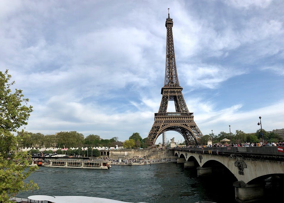 Eiffeltoren bij water en brug met blauwe lucht met wolken