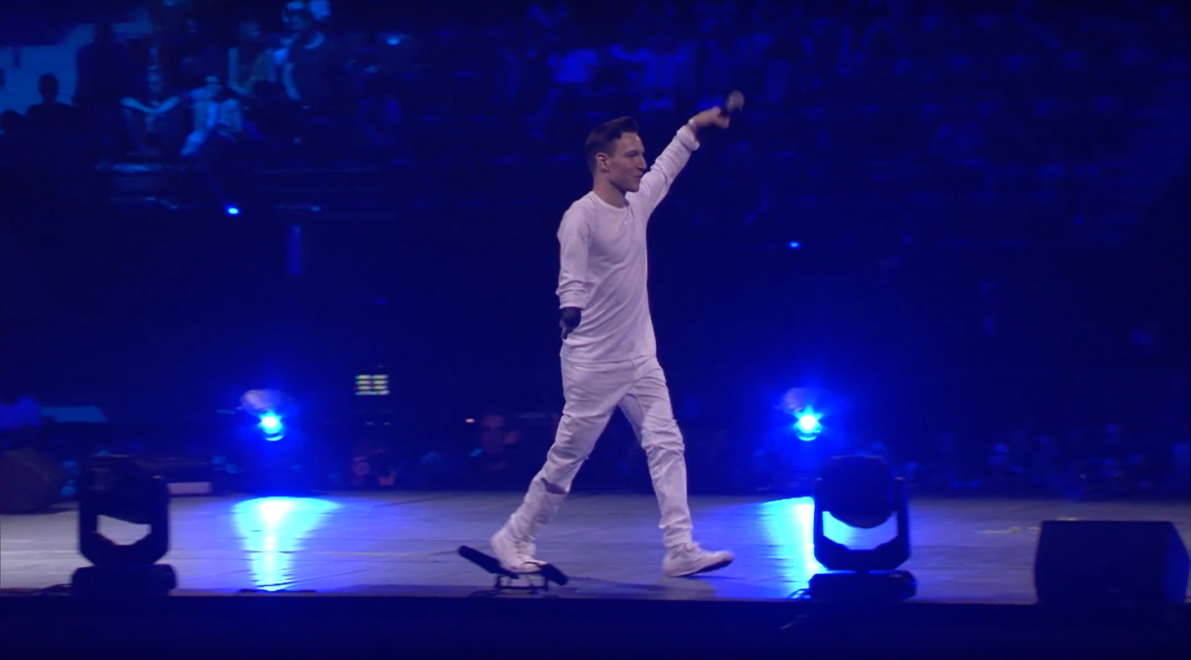Redouan Ait-Chitt in witte kleding met hand in lucht op het podium
