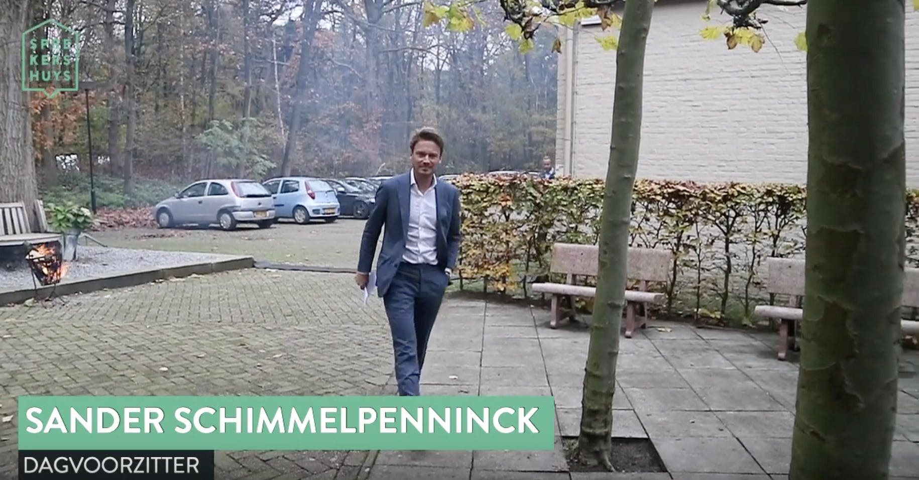 Sander Schimmelpenninck lopend buiten in blauw pak met tekst 'Sander Schimmelpenninck dagvoorzitter'