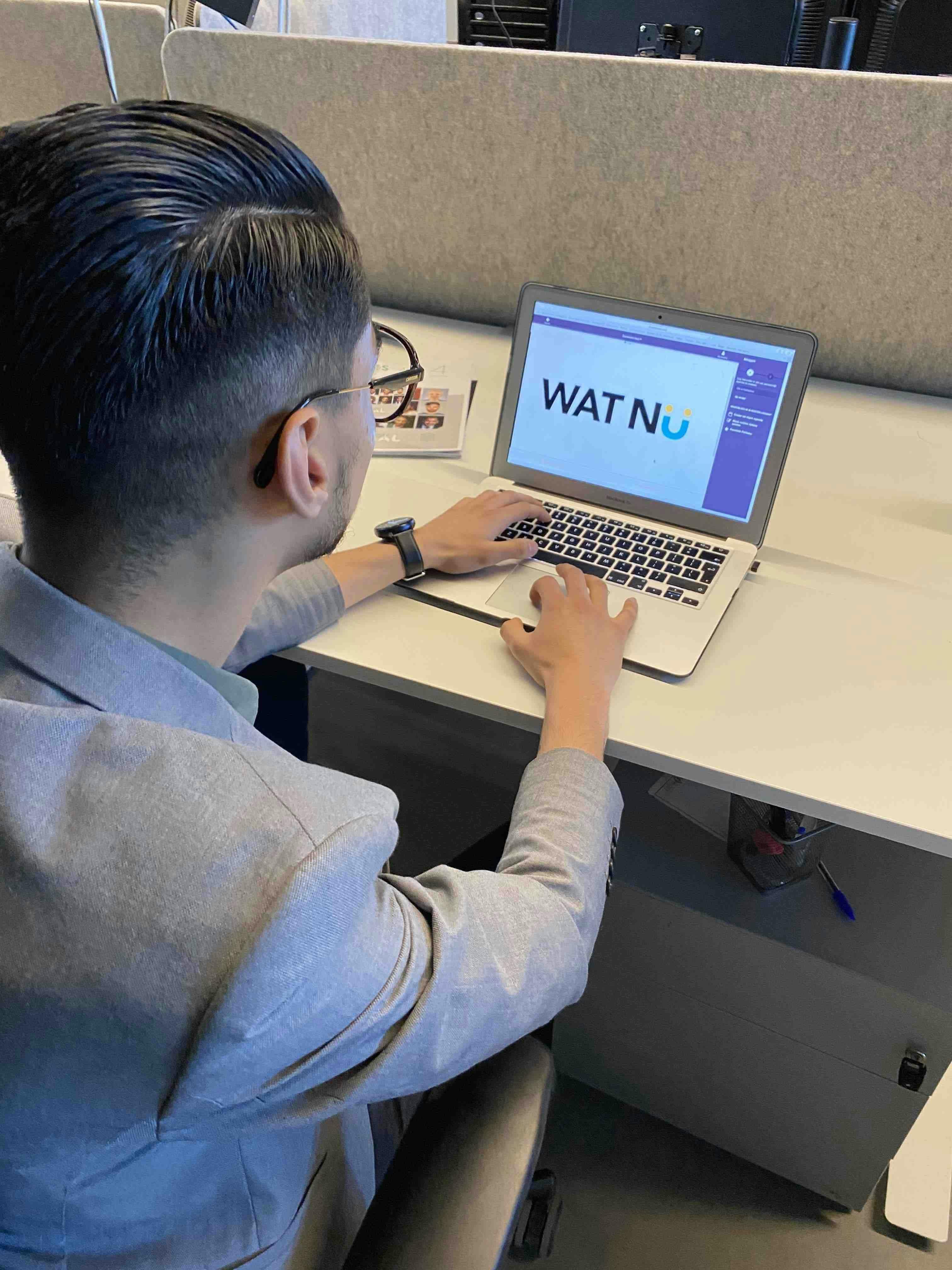 Man achter laptop bij bureau met de tekst 'wat nu'