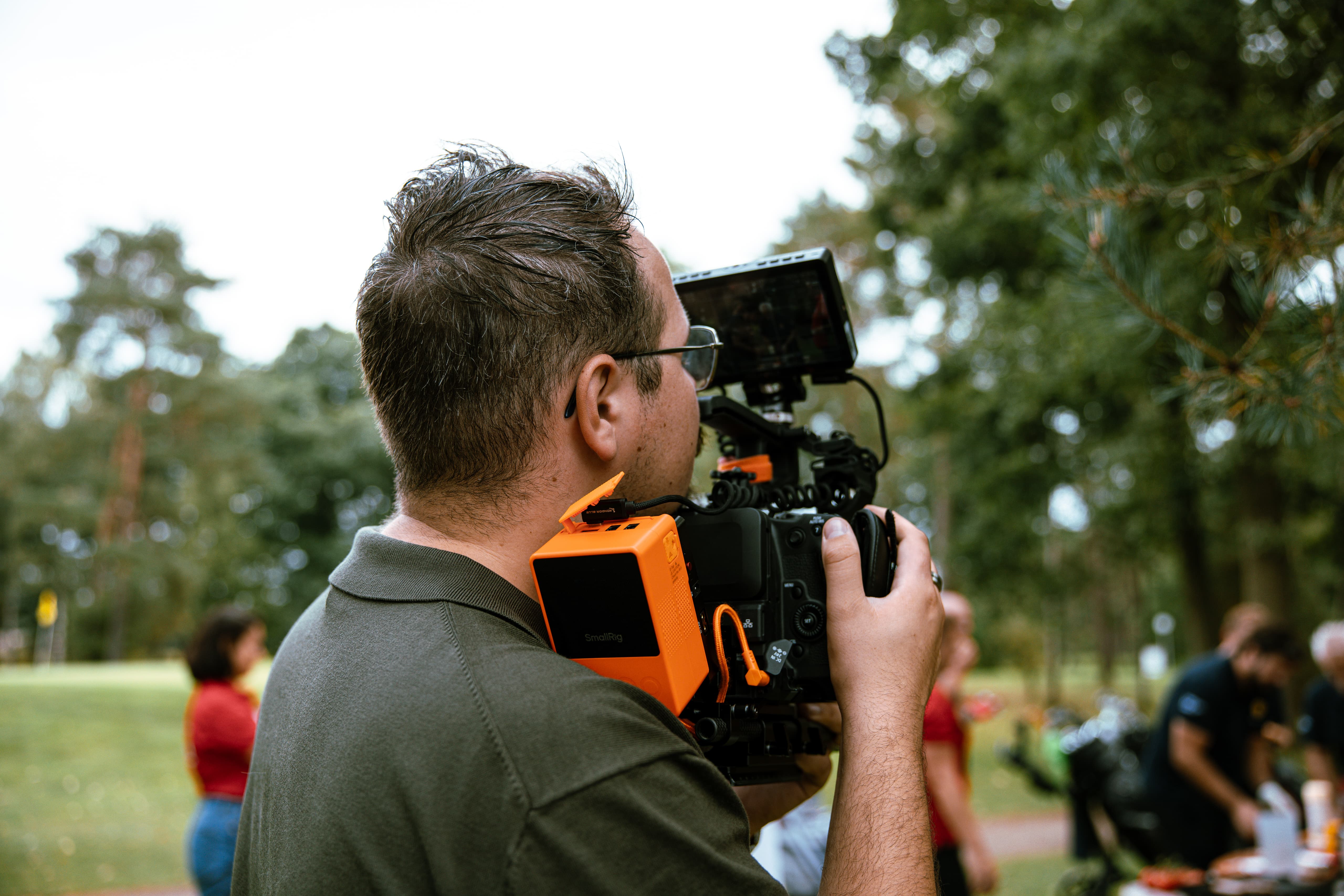 Bas met camera op schouder op golfbaan