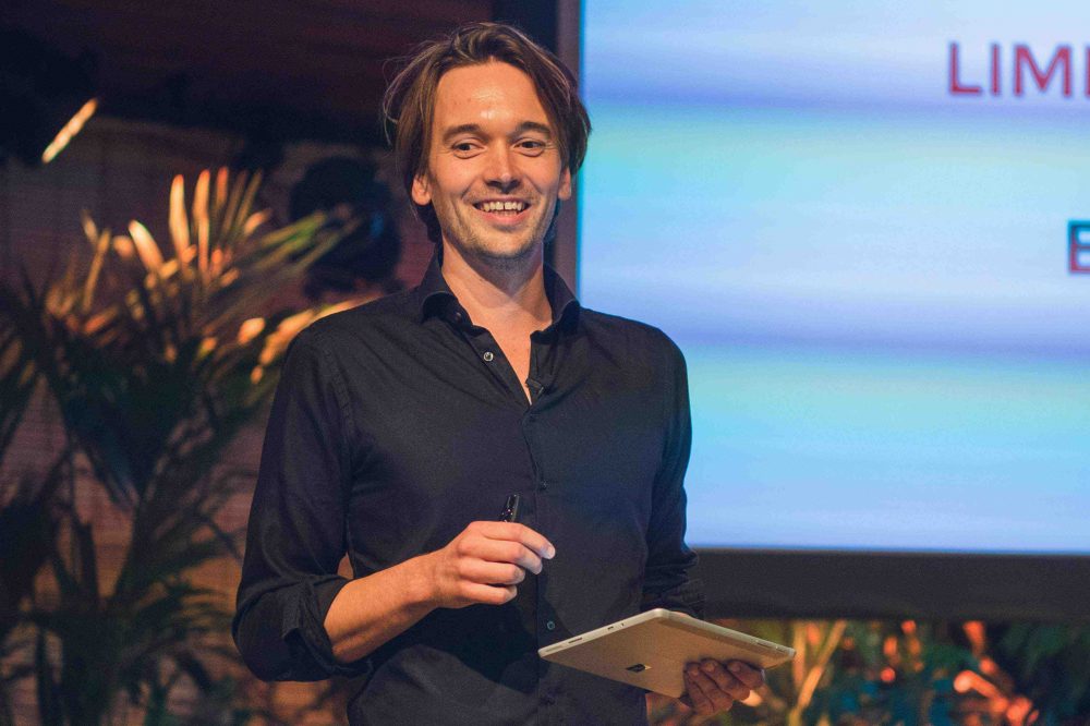 Spreker Joel aan 't Goor op het podium met tablet