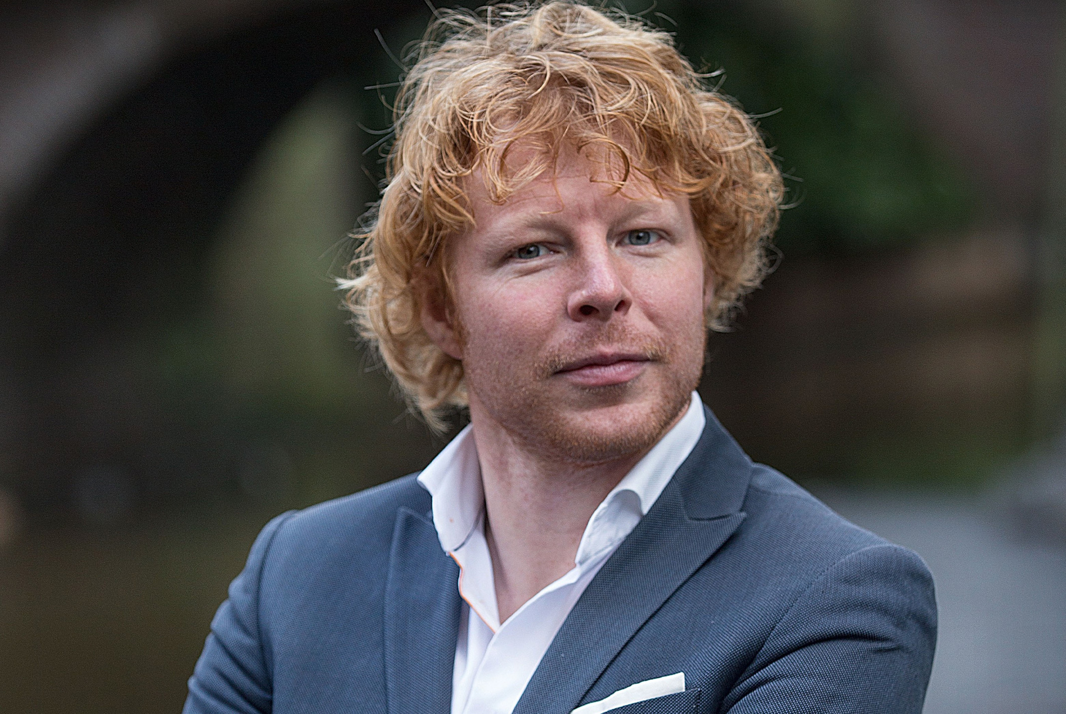 Ben Woldring met armen over elkaar poserend buiten in pak