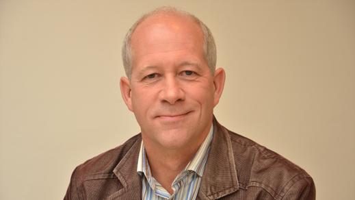 Man met een bruine jas aan op een licht beige achtergrond