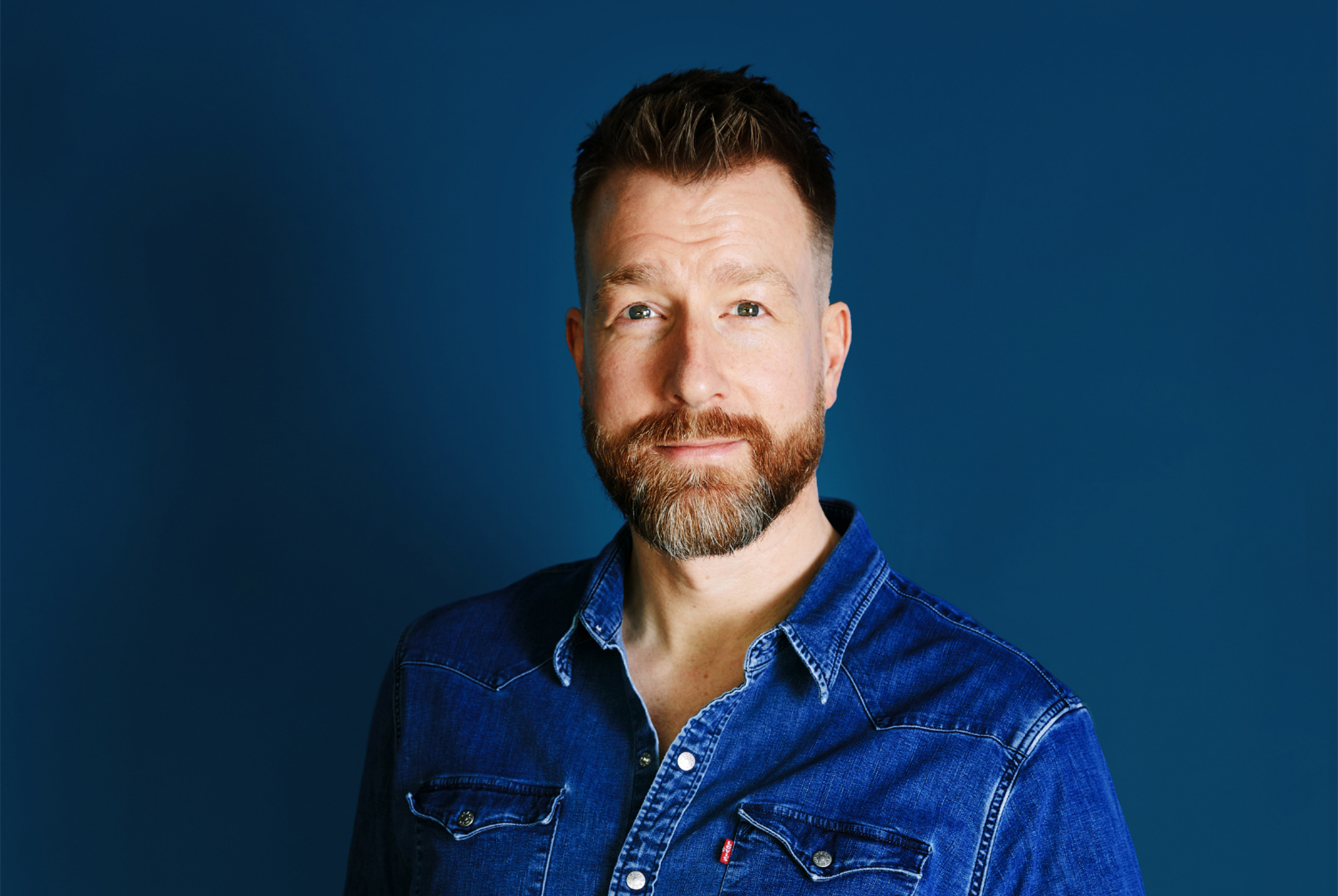 Man in het blauw gekleed met ene blauwe achtergrond