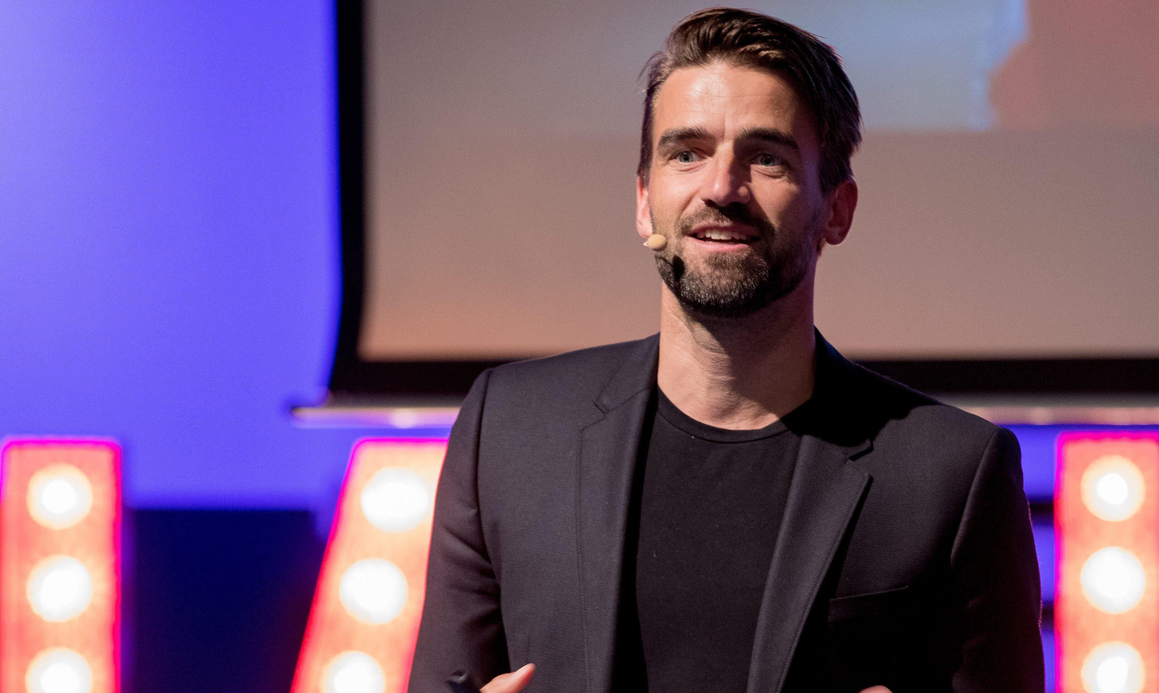 Mark Tuitert voor een blauwe achtergrond en digiboard