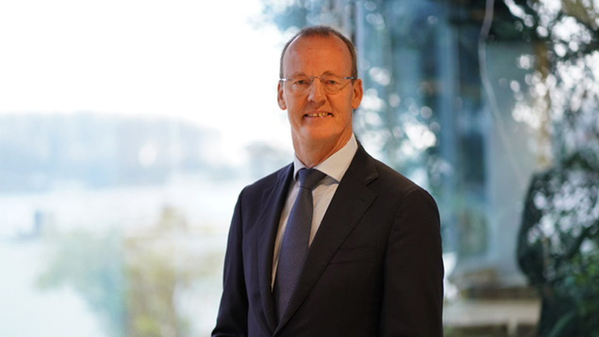 Man in pak die voor een raam staat