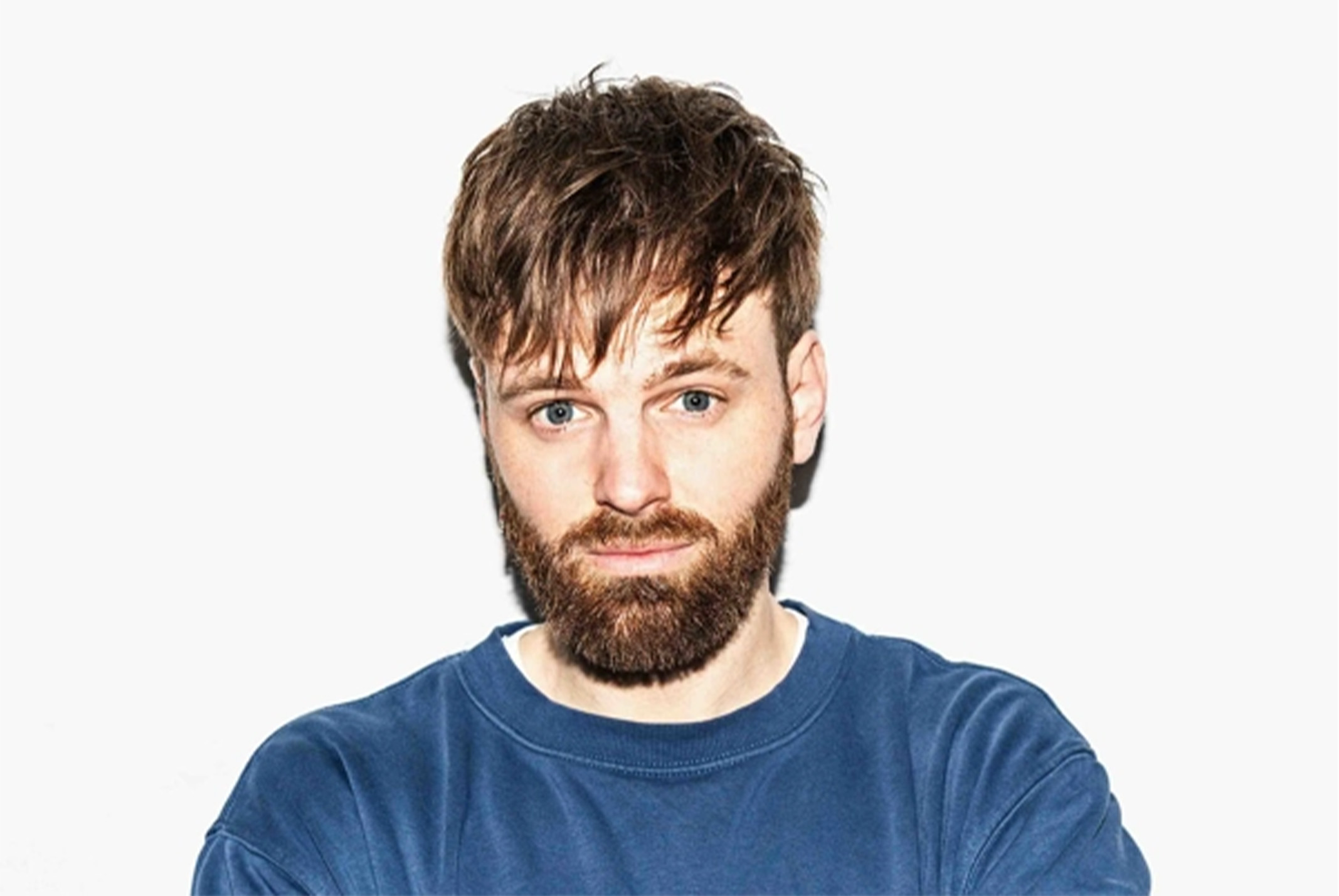 Tim Hofman voor witte backdrop en blauwe sweater