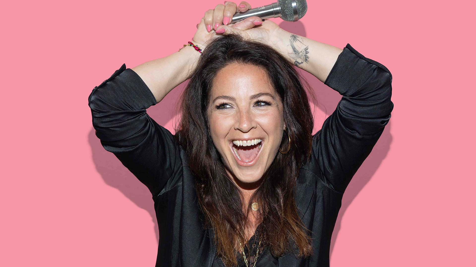 Blije vrouw zwart gekleed met een roze achtergrond