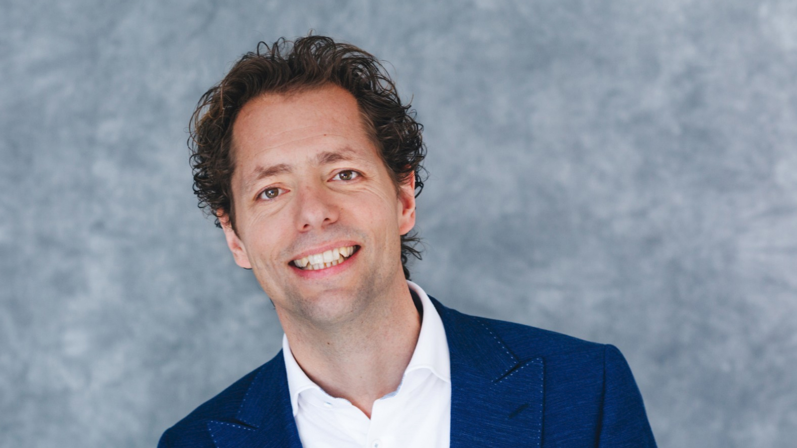 Joost van der Weijden lachend met grijze achtergrond