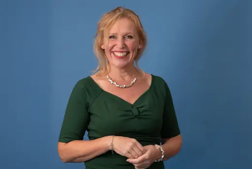 Froukje Weidema met groene jurk voor blauwe achtergrond