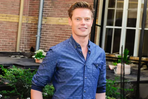 Marco Aarink in blauw overhemd voor bakstenen gebouw