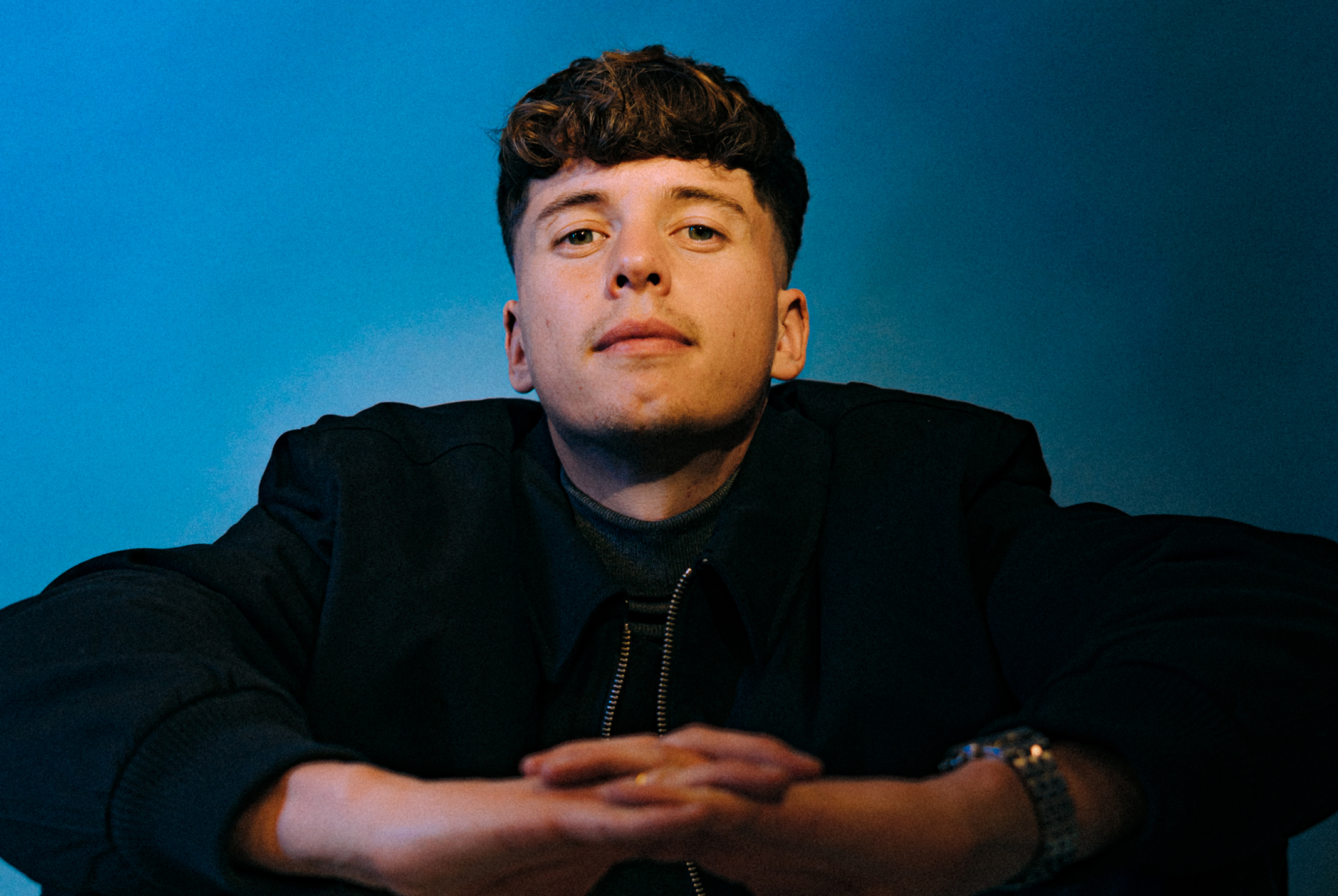 Man in zwarte kleding met een blauwe achtergrond