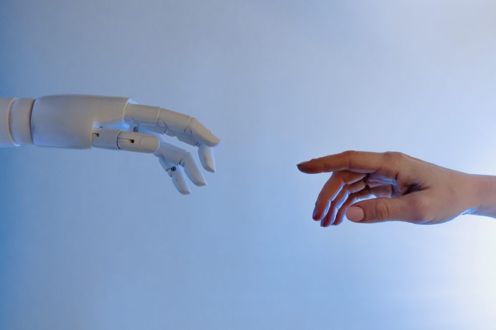 Een menselijke vinger die bijna een robot vinger aanraakt