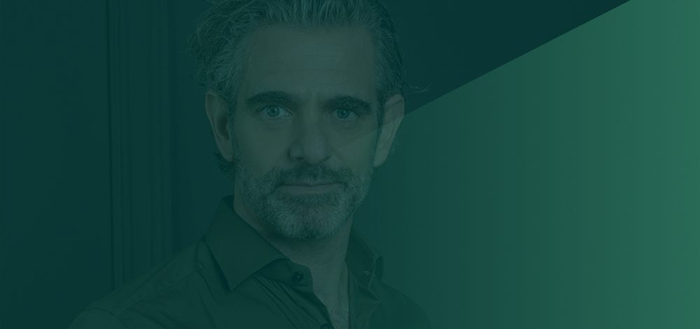 Foto van raymond loze achter een groene backdrop