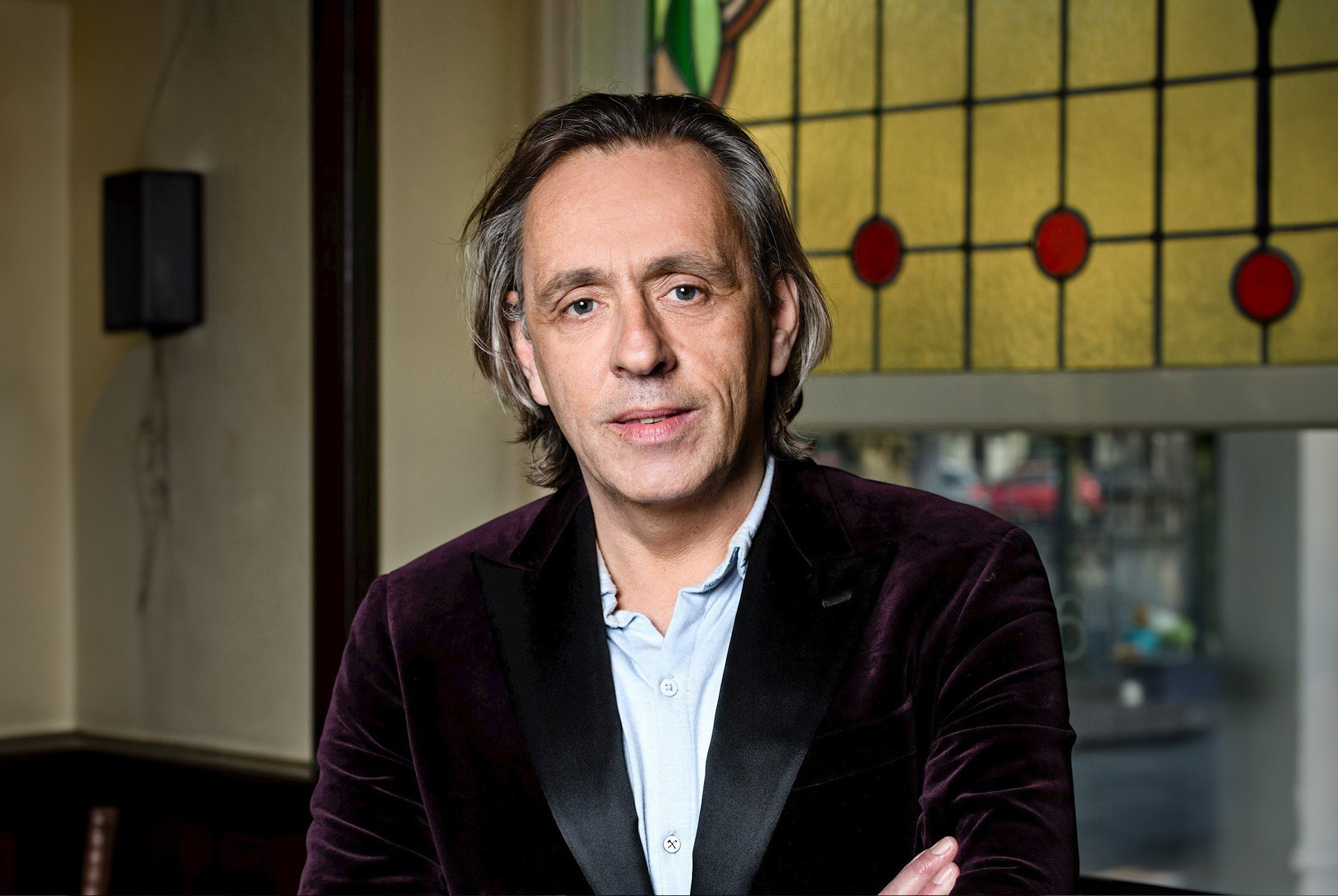 Marcel van Roosmalen gele achtergrond en een rode jas