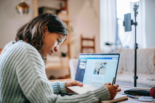 meisje achter laptop schrijft in boekje
