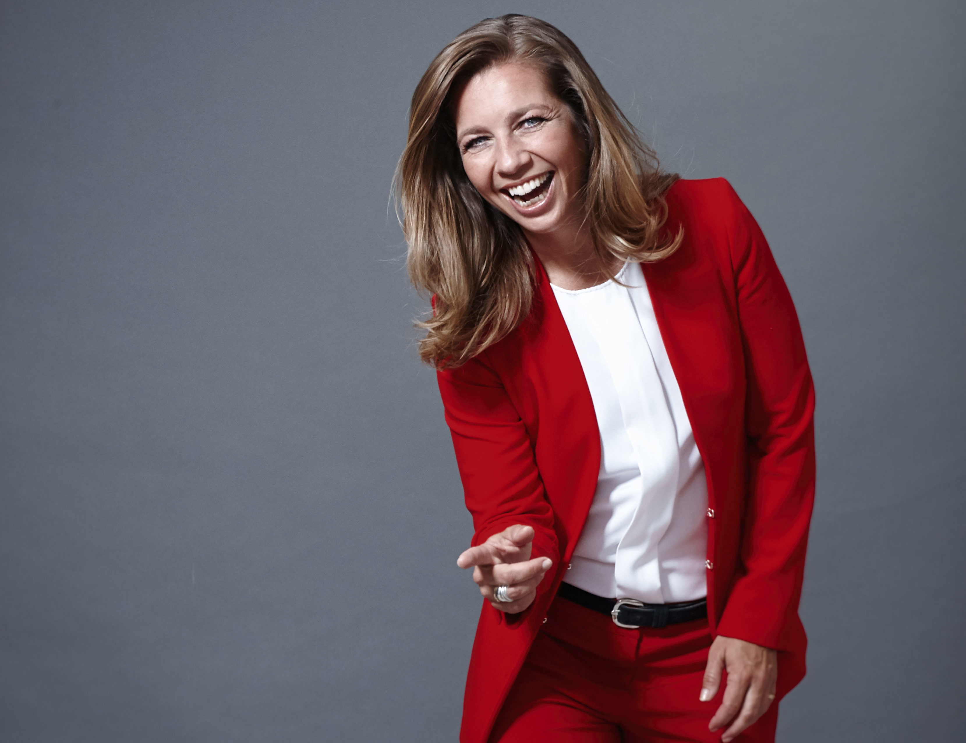 Pauline de Wilde lachend op de foto in een rood pak