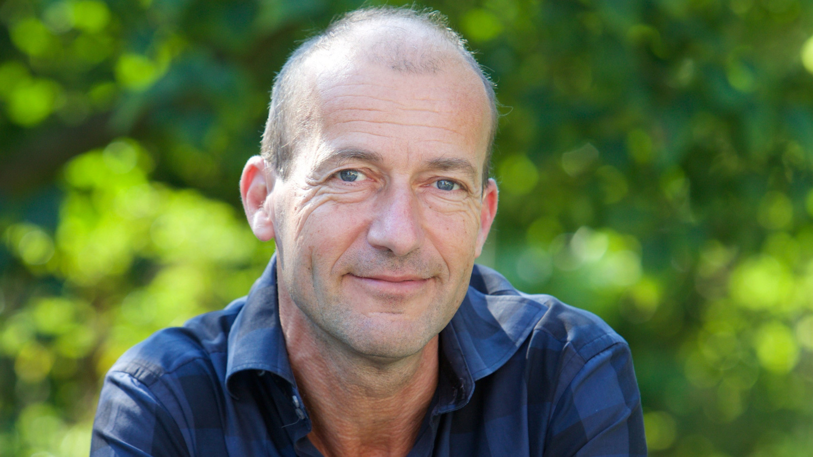 Reinier van den Berg glimlachend in blauwe blouse buiten