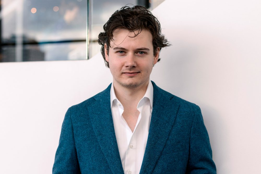 Remy Gieling in blauwe blazer voor witte muur