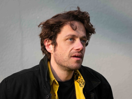 Camiel Jansen in geel overhemd en zwarte jas