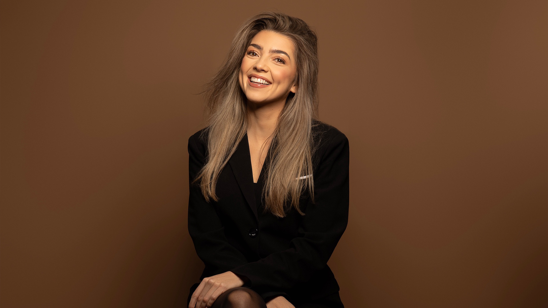 Vrouw met los haar gekleed in donker rood op een bruine achtergrond