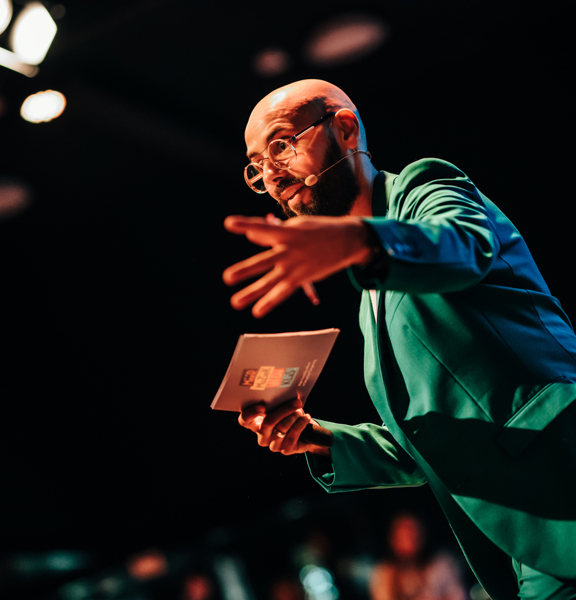 Karim Amghar in groene colbert met kaart in hand sprekend