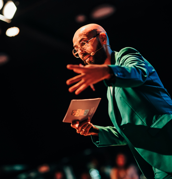 Karim Amghar in groene colbert met kaart in hand sprekend