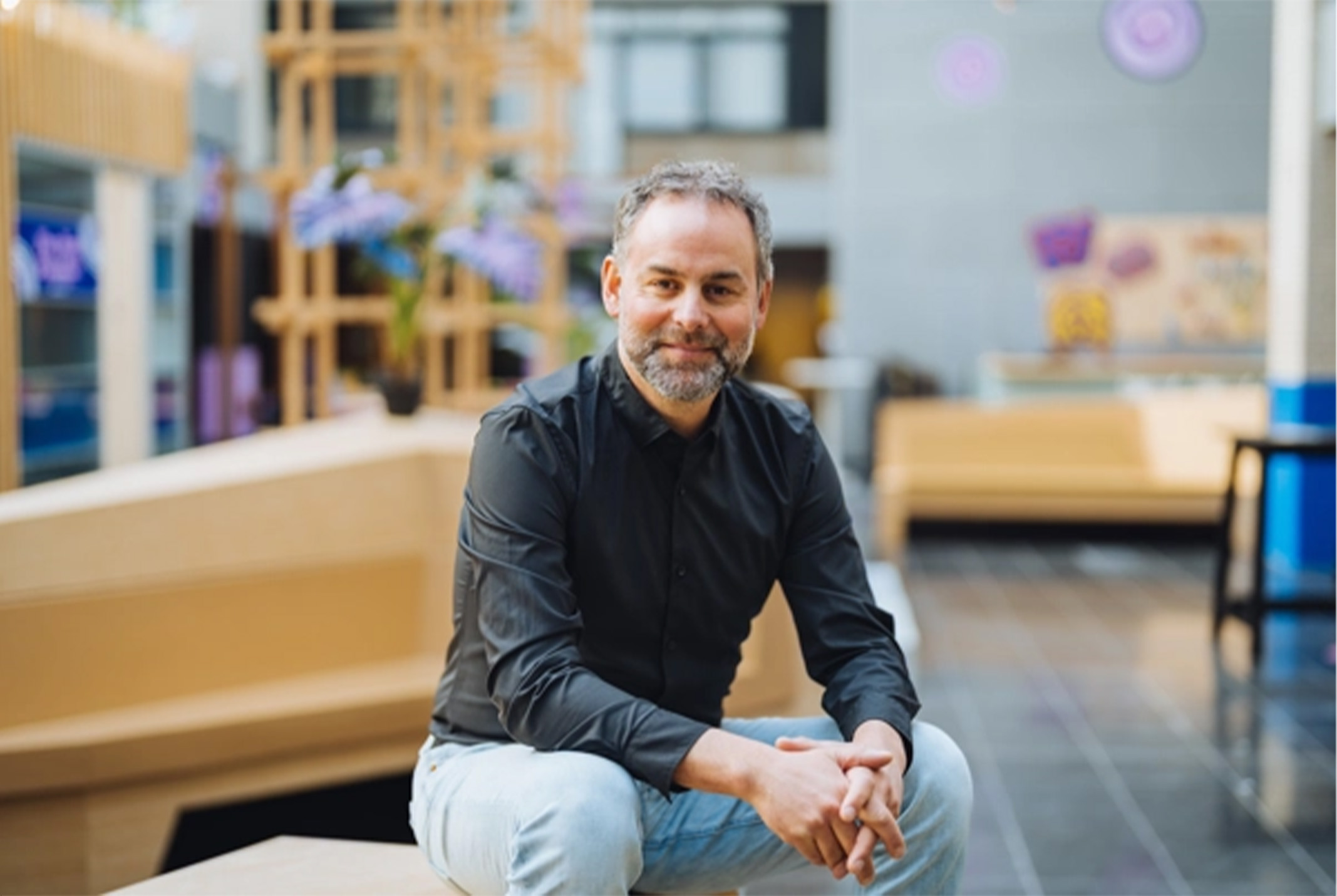 Patrick Willer in open ruimte met houten meubilair