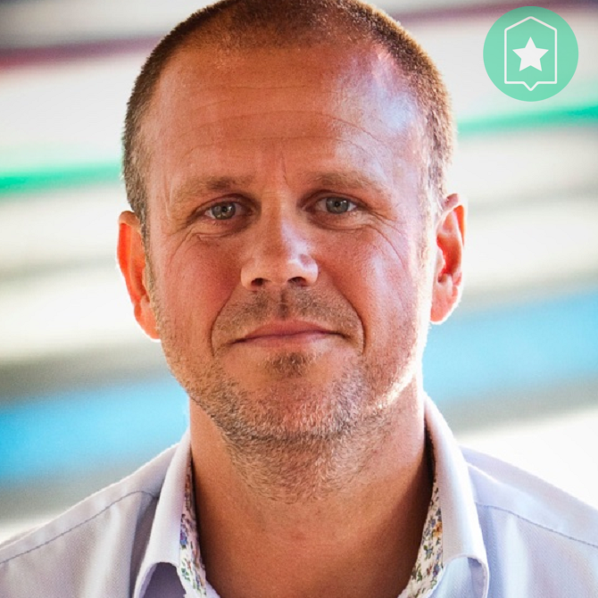 Ynzo van Zanten poserend in witte blouse bij kleuren achtergrond