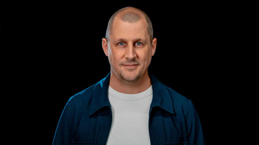 Man in een wit shirt en blauw jasje op een zwarte achtergrond