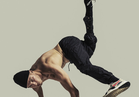 Redouan Ait-Chitt dansend met voeten in de lucht zonder shirt bij witte achtergrond